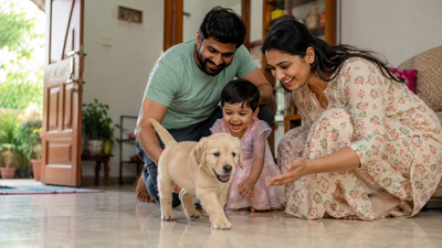 A family welcoming a happy, healthy puppy into their Indian home on its first day.